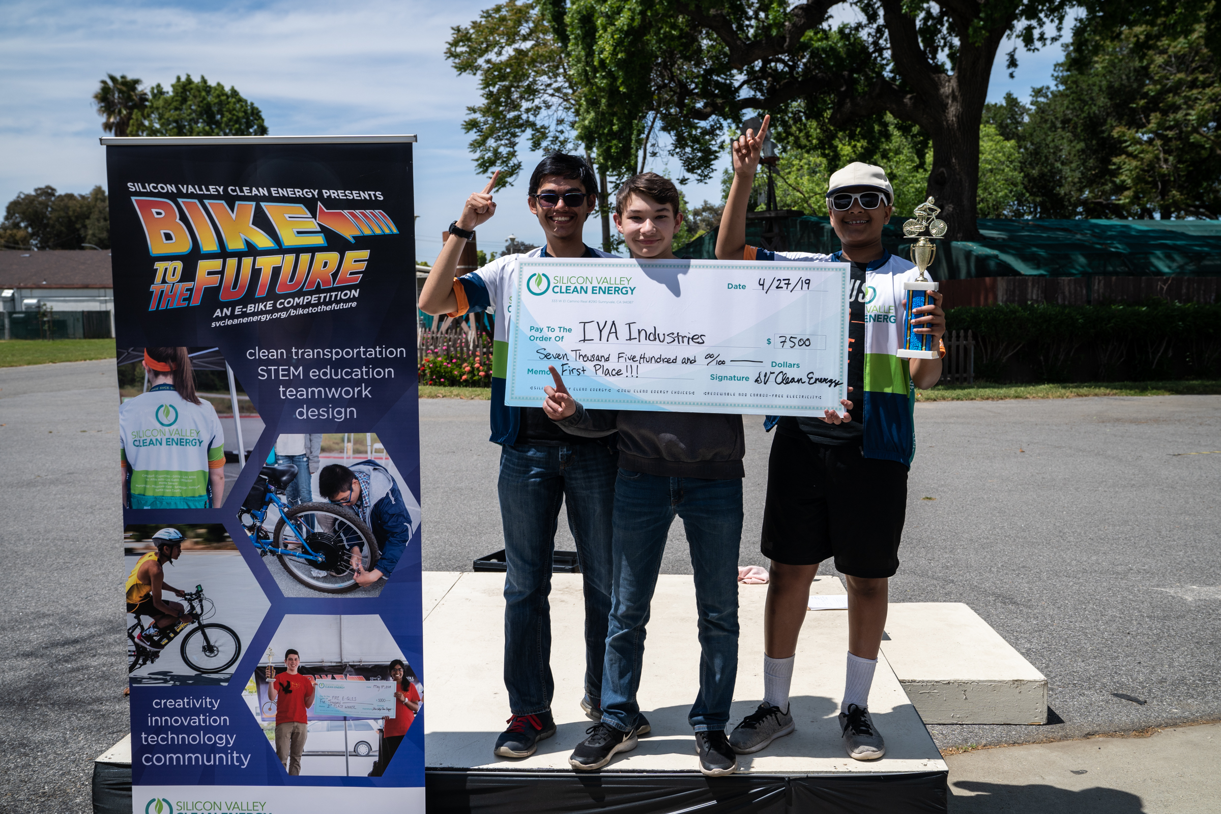 Winning Team of three high school boys holding trophy and giant check