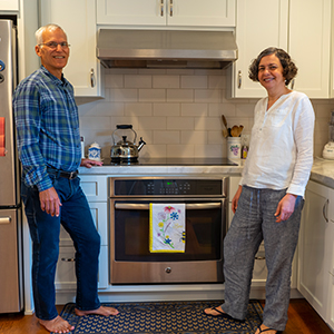 Couple standing in kitchen on either side of induction stove