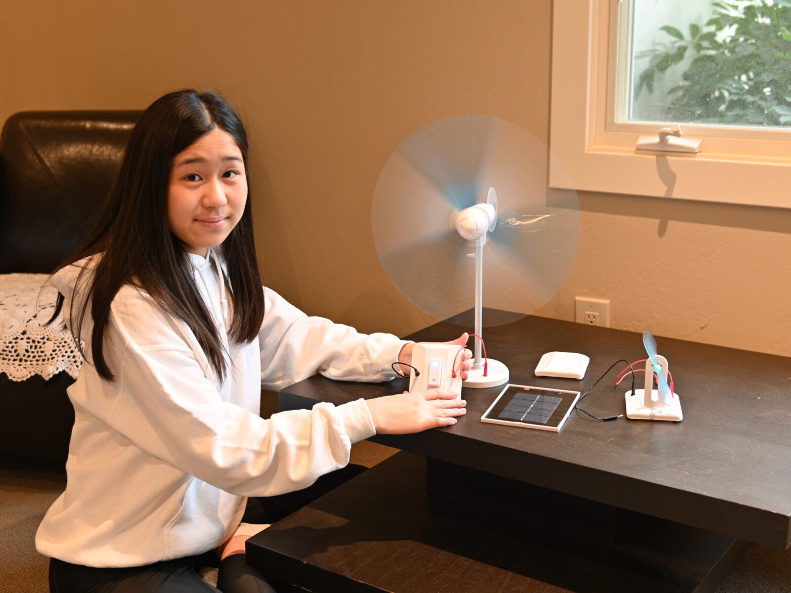 Youth sitting next to model of wind turbine and small solar panel