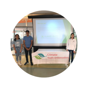 Climate Youth Ambassador participants standing in front of table and presentation at library